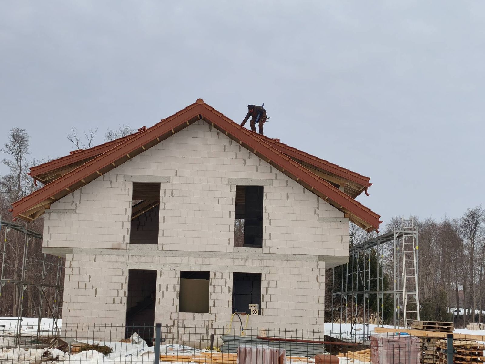 Meistrai kloja raudonas čerpes ant naujo namo